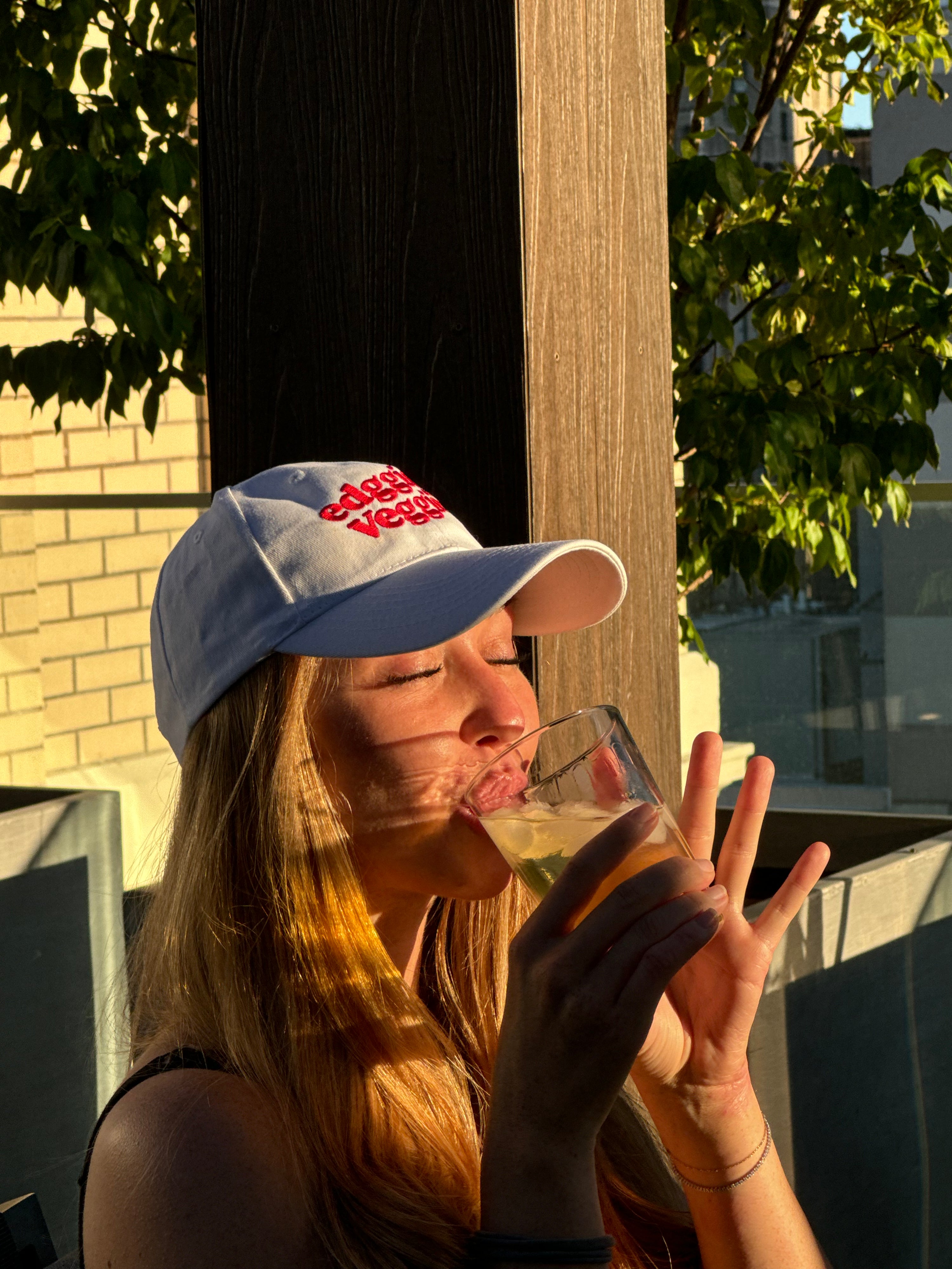 Girl sipping her summer cocktail with the edggies veggies hat